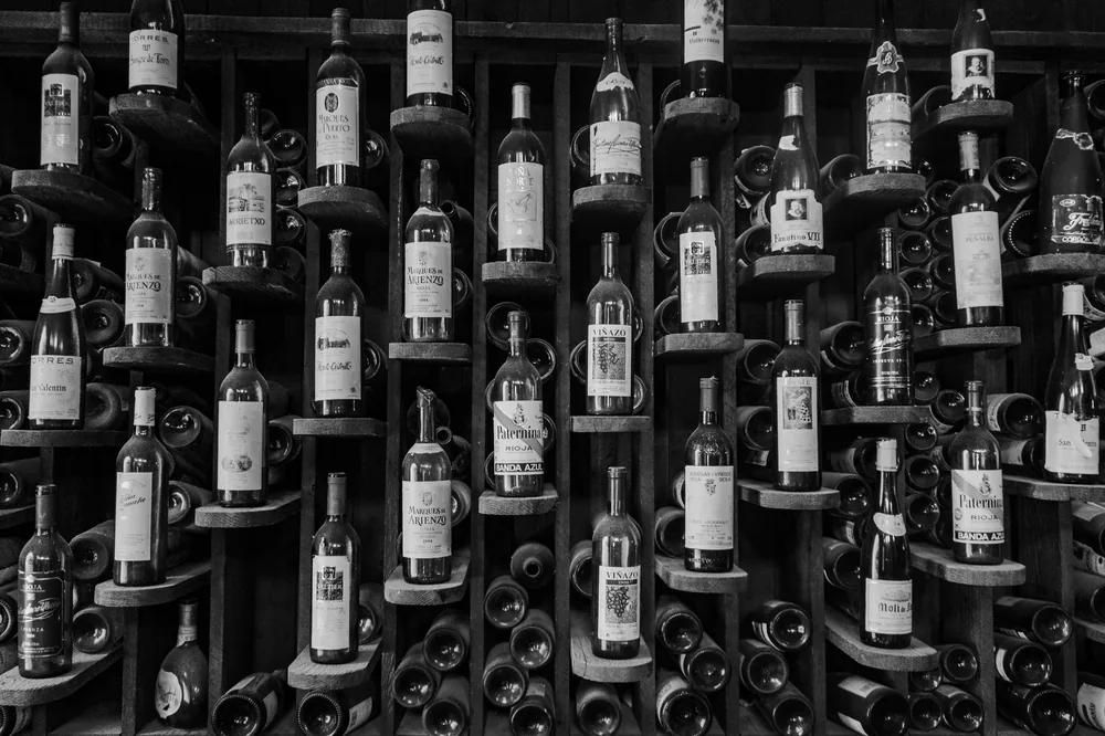 A black and white photo showcasing an elegant wine rack filled with various bottles