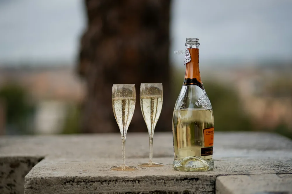 A bottle of wine and two glasses of champagne