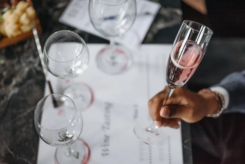 A close-up of a wine tasting setup with glasses and a hand holding champagne