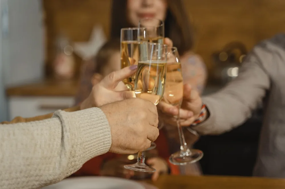 A close-up of hands raising champagne glasses in a celebratory toast indoors