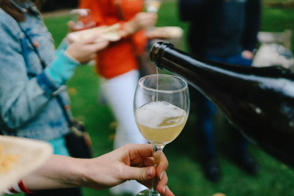 A close-up of wine being poured into a glass during a casual outdoor gathering