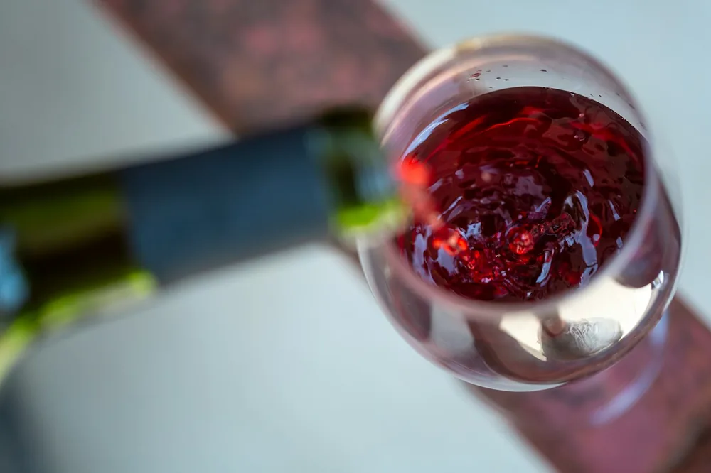 A close-up shot capturing the graceful pour of a deep red wine into a crystal-clear glass, highlighting the rich color and inviting aroma