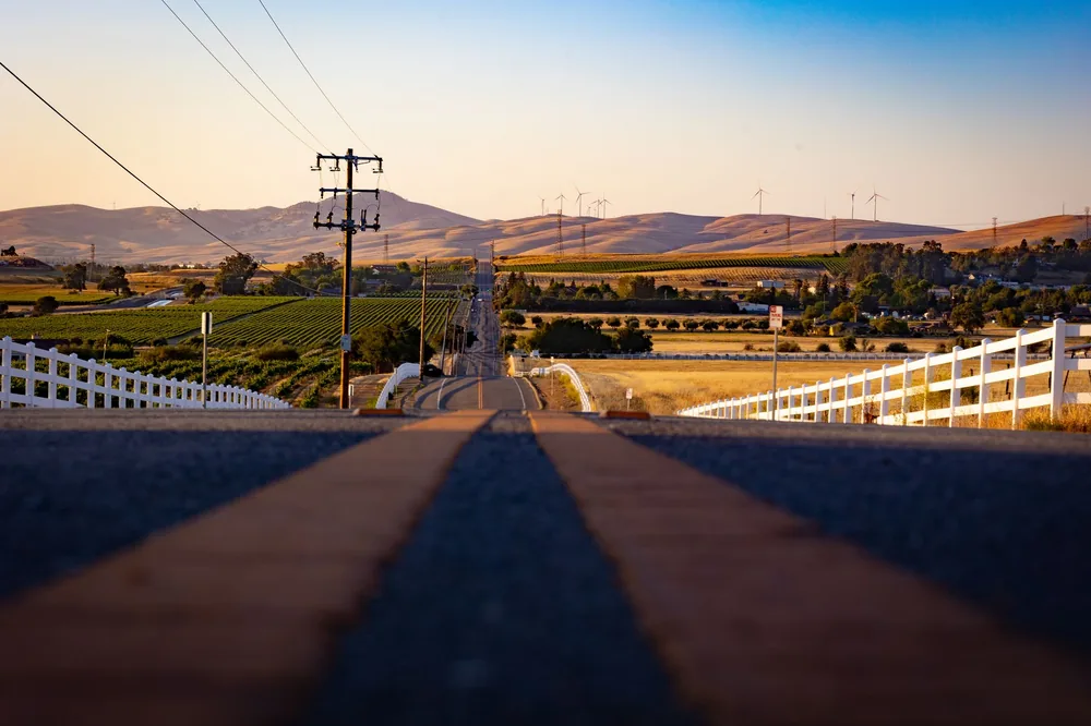 A country road in Livermore, CA with vineyards and windmills at sunset