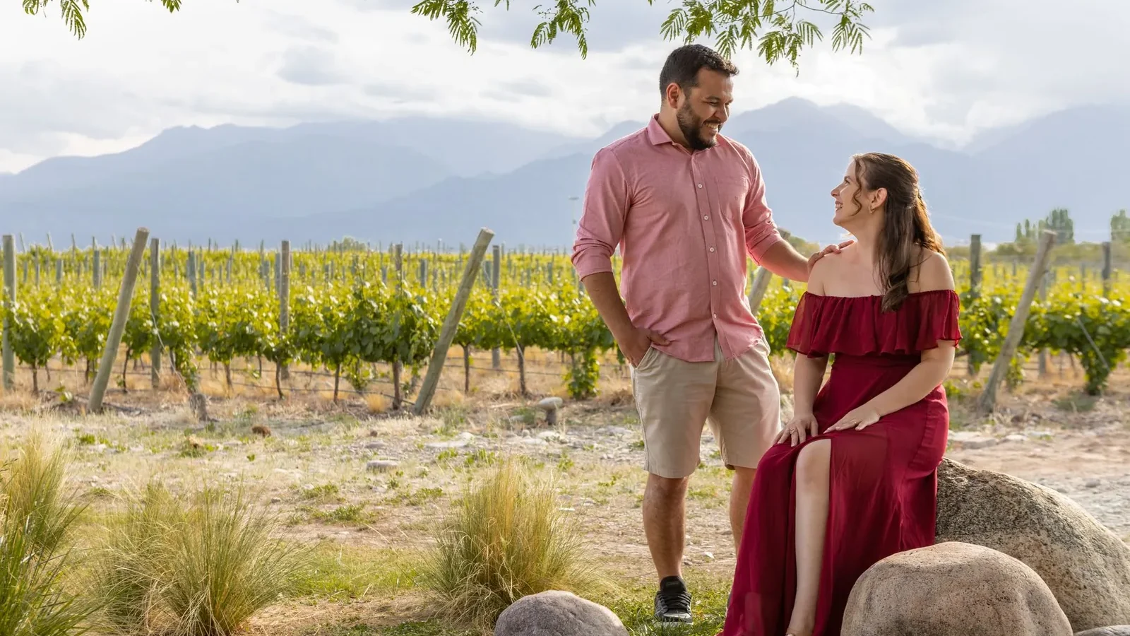 A couple enjoying a romantic moment in a scenic vineyard with mountains in the background