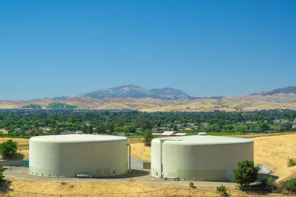 A couple of large tanks sitting on top of a dry grass field