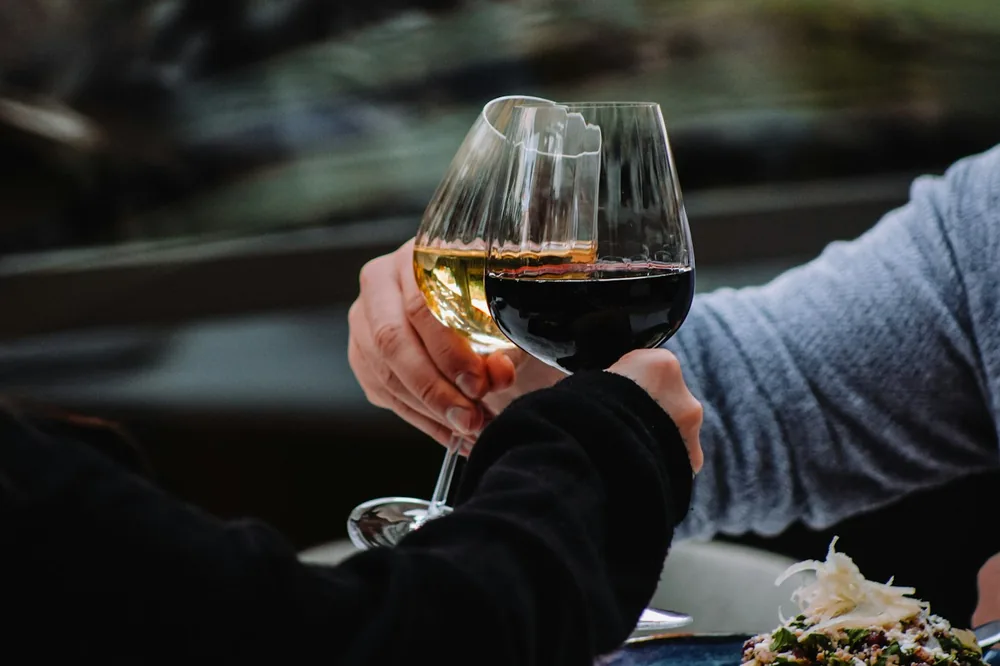 A couple of people holding hands over a glass of wine