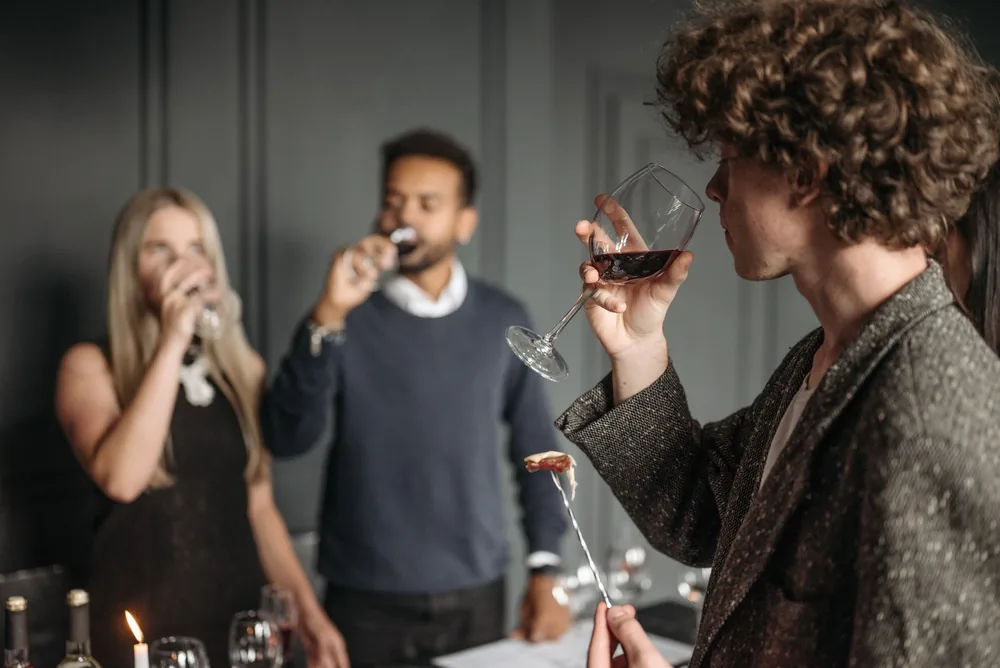 A diverse group of adults enjoying a wine tasting event indoors with a blurred background