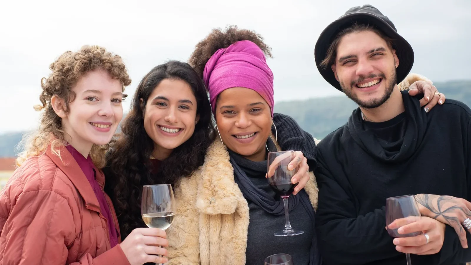A diverse group of friends enjoying wine together outdoors, smiling and celebrating friendship