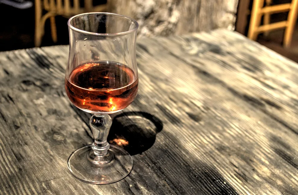A glass of rose wine sits elegantly on a rustic wooden table, capturing a relaxed dining atmosphere