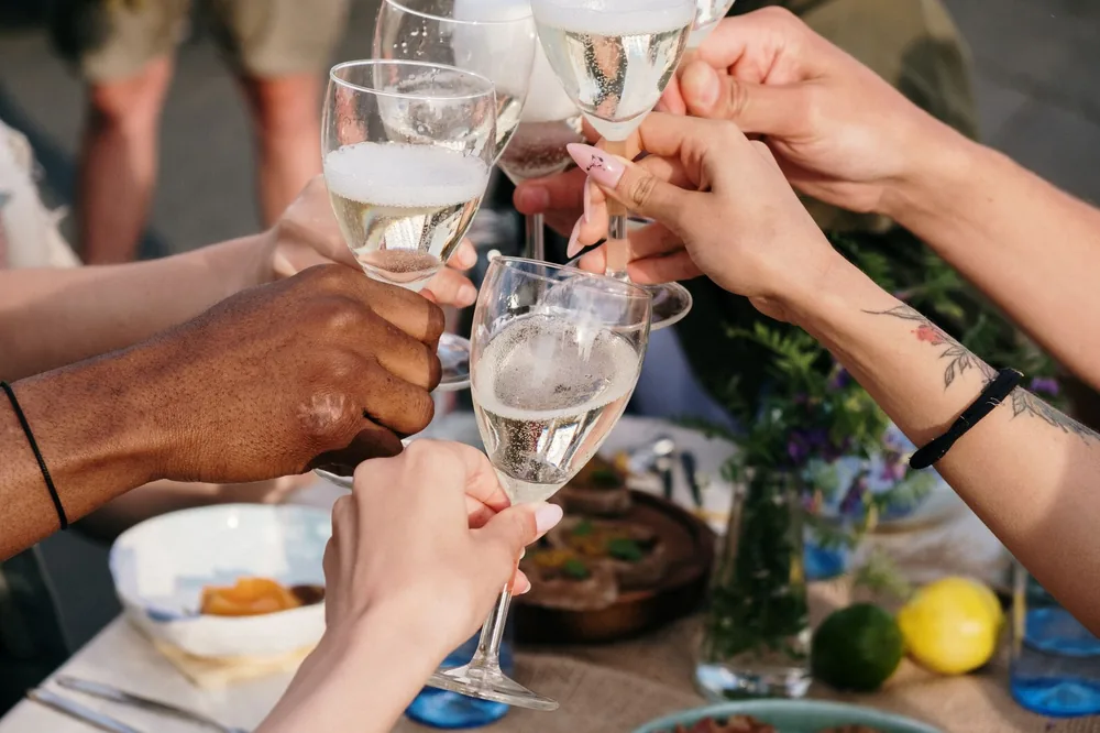 A group of diverse friends toasting with wine glasses during an outdoor summer gathering