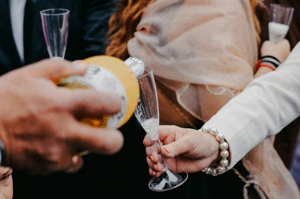 A group of people standing around each other holding wine glasses