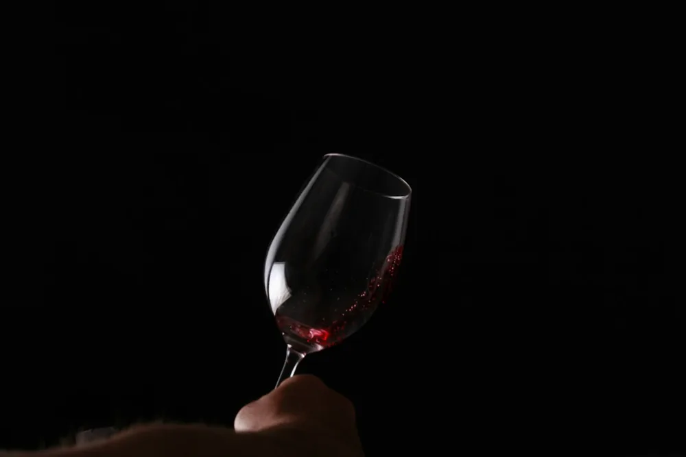 A hand holding a wine glass with red wine in it