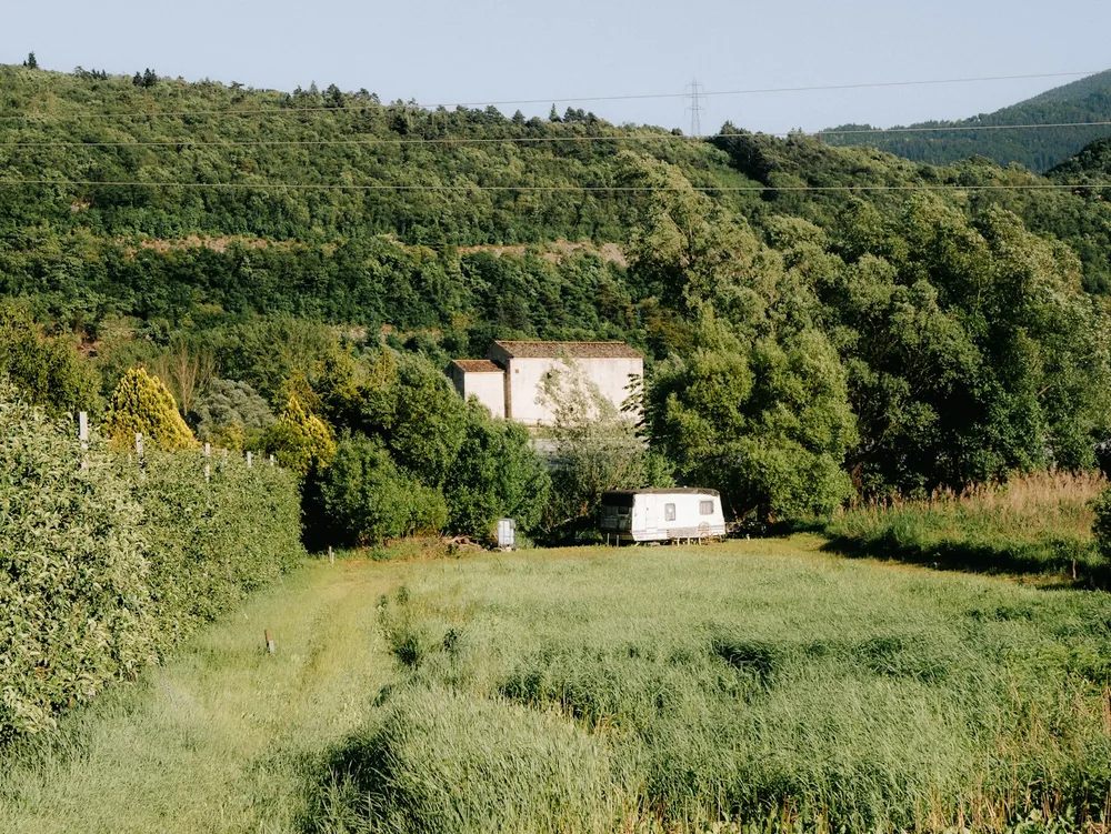 A house and trailer nestled in a lush, green landscape