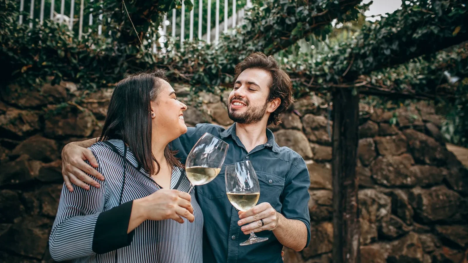 A joyful couple enjoys white wine outdoors, creating a celebratory moment