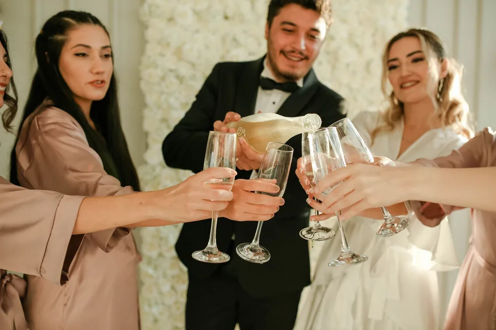 A joyful wedding moment with champagne being poured into glasses for a toast among friends