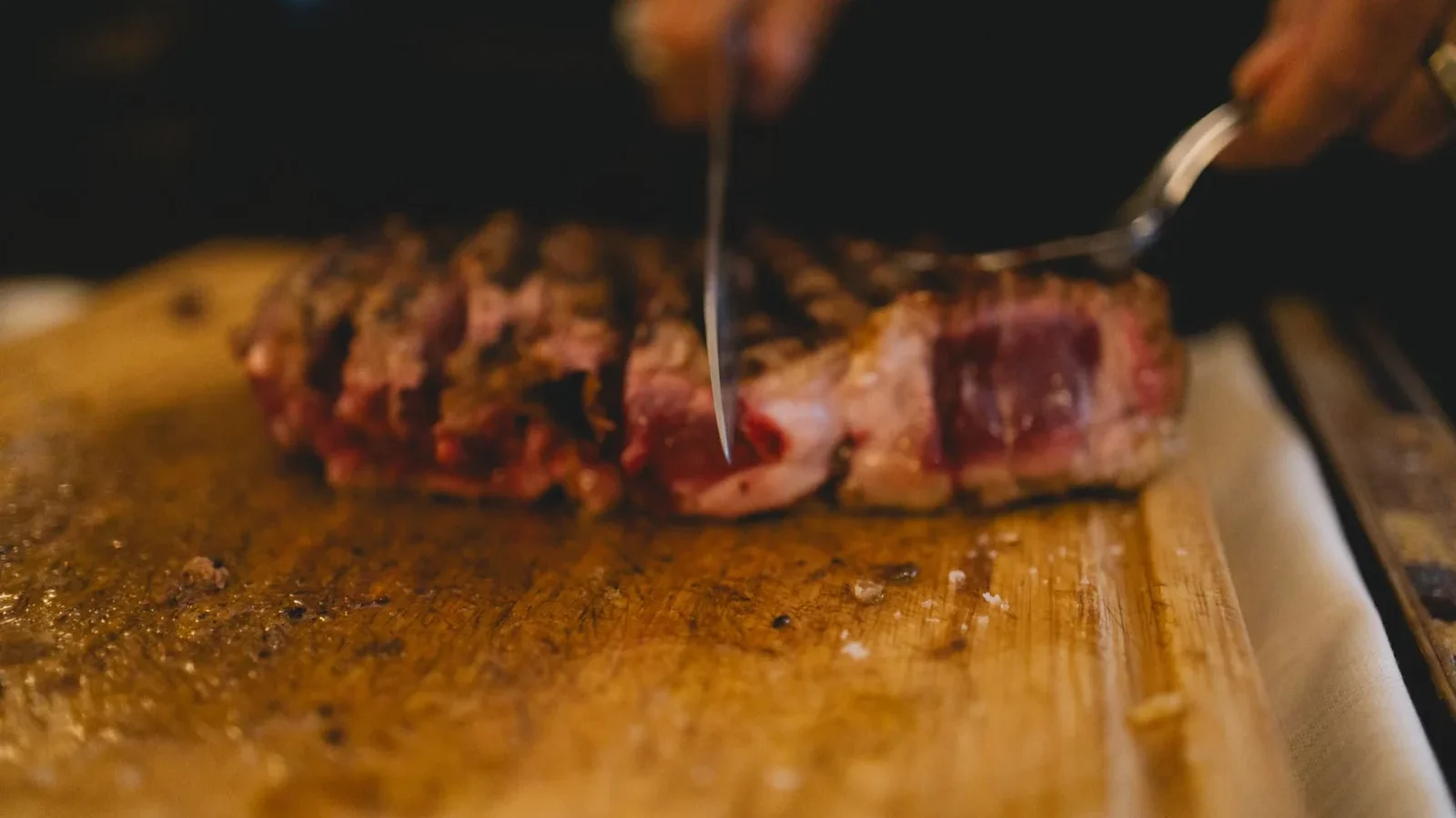 A juicy steak being expertly carved on a wooden board