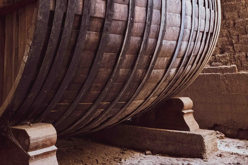 A large wooden wine barrel in an ancient wine cellar, highlighting the historic architecture