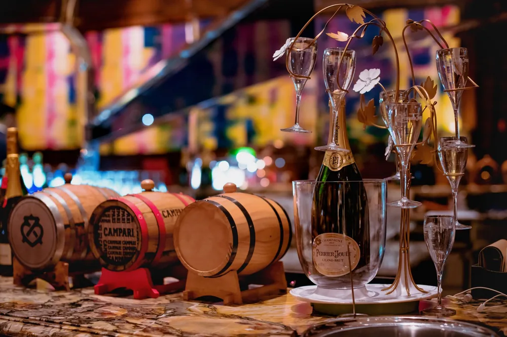 A luxurious bar with wooden barrels, champagne bottles, and glasses set in a atmosphere