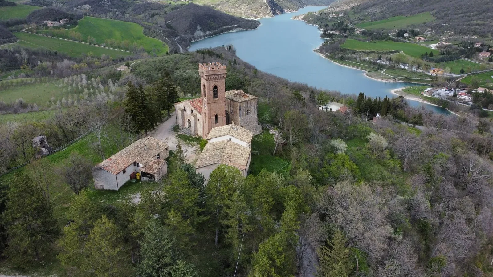 A medieval village surrounded by lush mountains and a tranquil lake