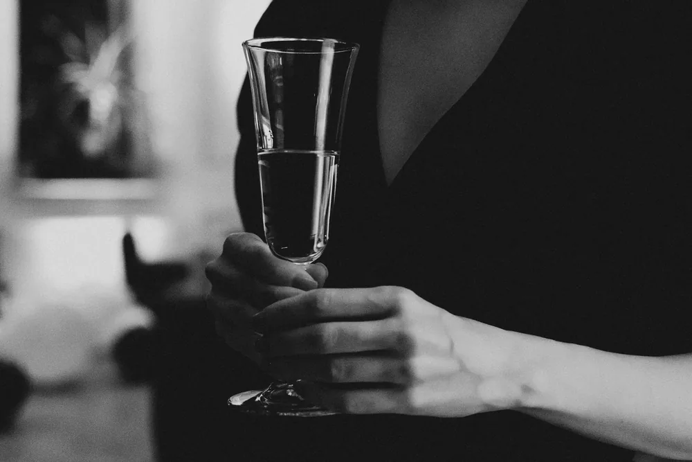 A monochrome photo capturing a woman elegantly holding a champagne glass indoors