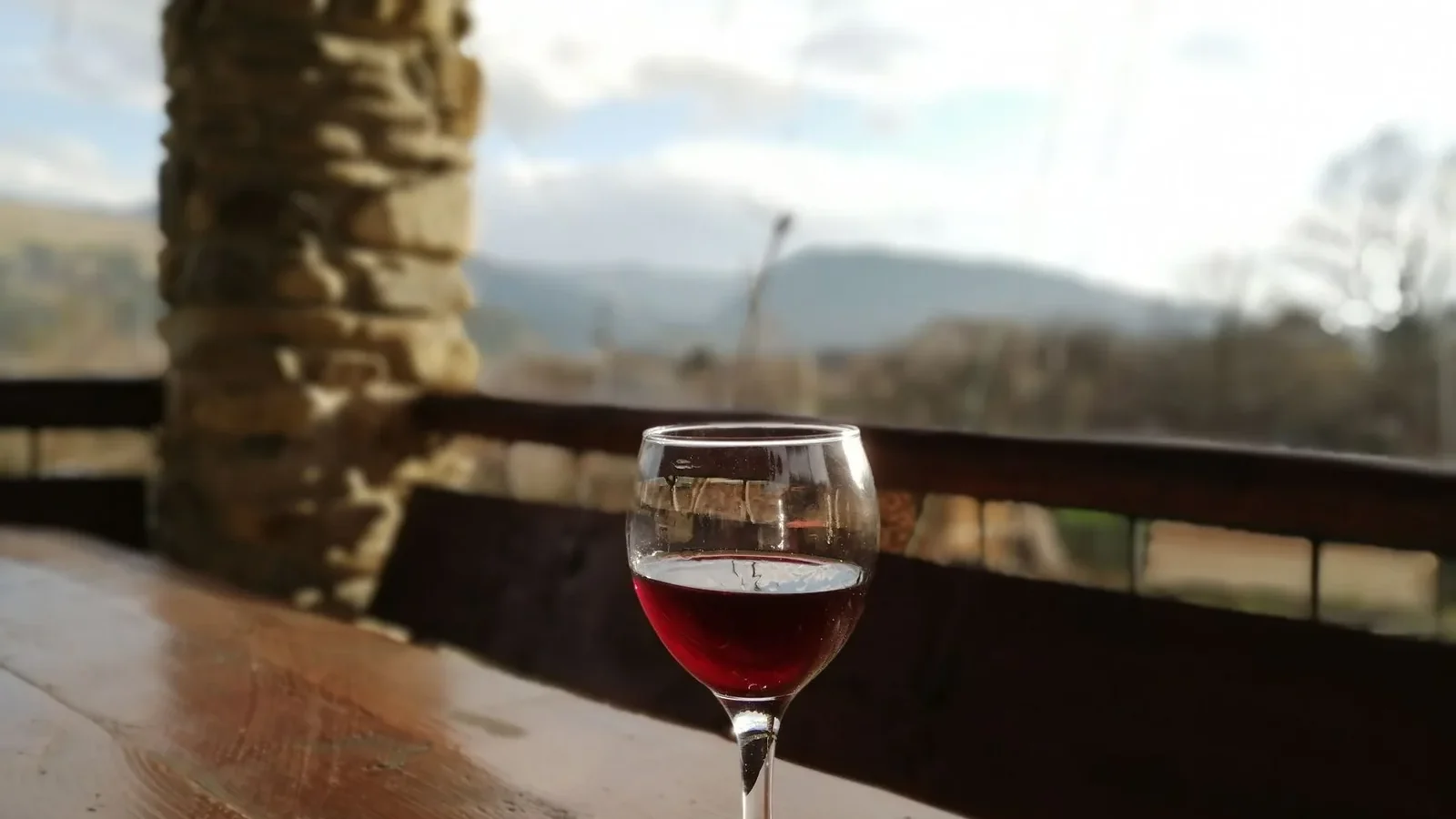A peaceful outdoor setting with a glass of red wine on a wooden table