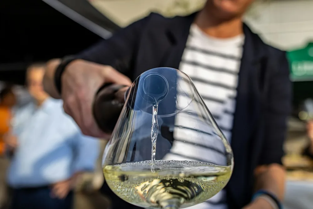A person pouring a glass of white wine