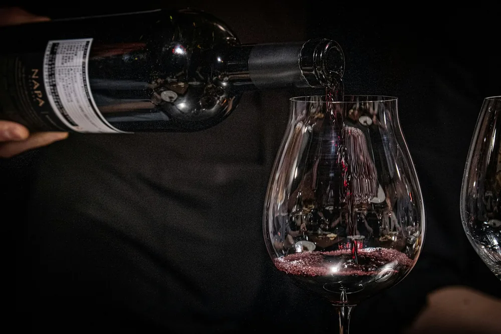 A person pouring red wine into a wine glass