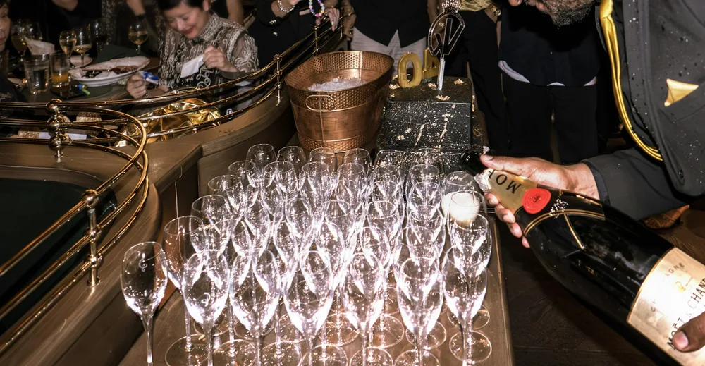 A person pours champagne into numerous glasses at an event