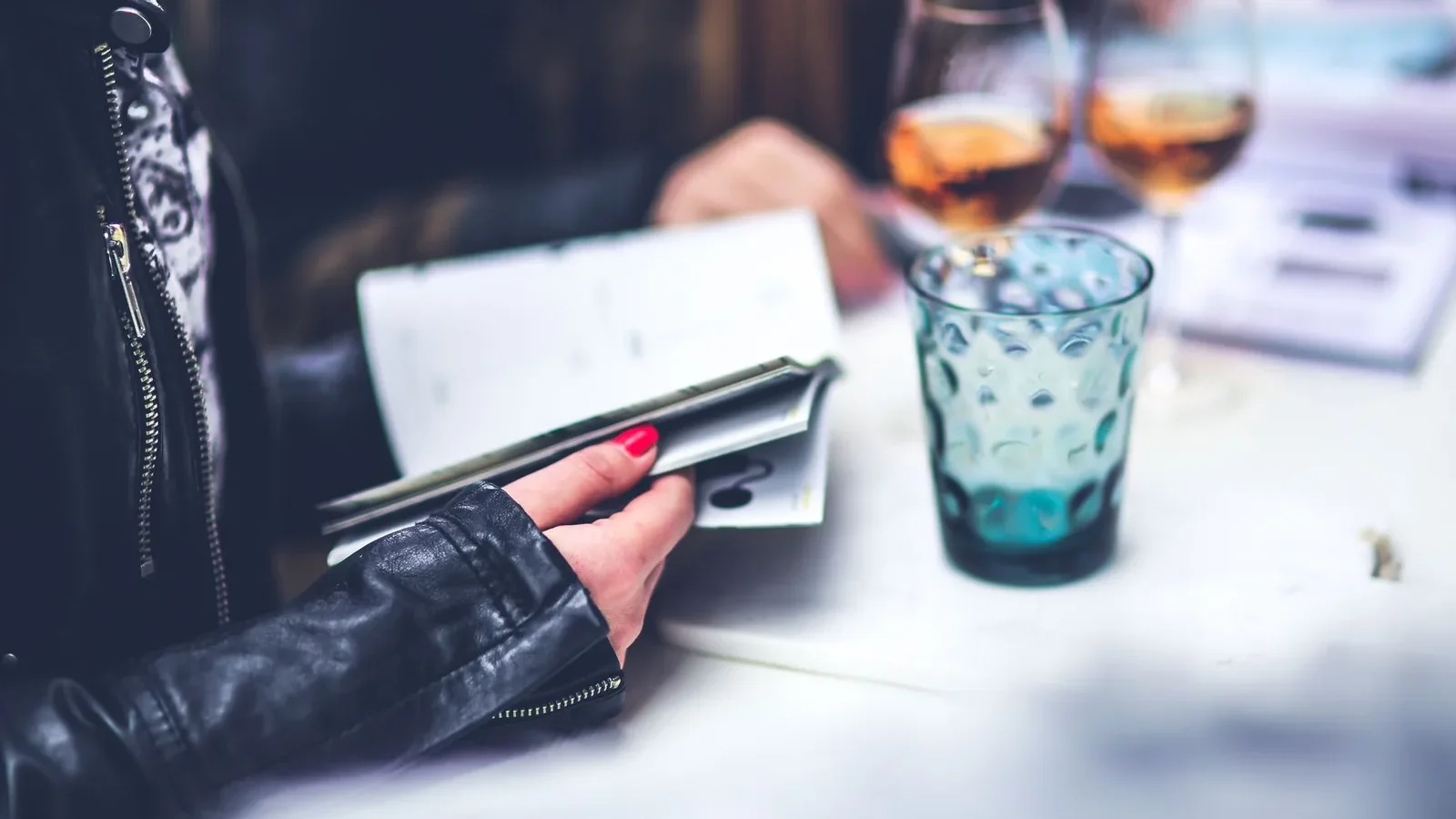 A person reads at a table with drinks, creating a relaxing dining atmosphere