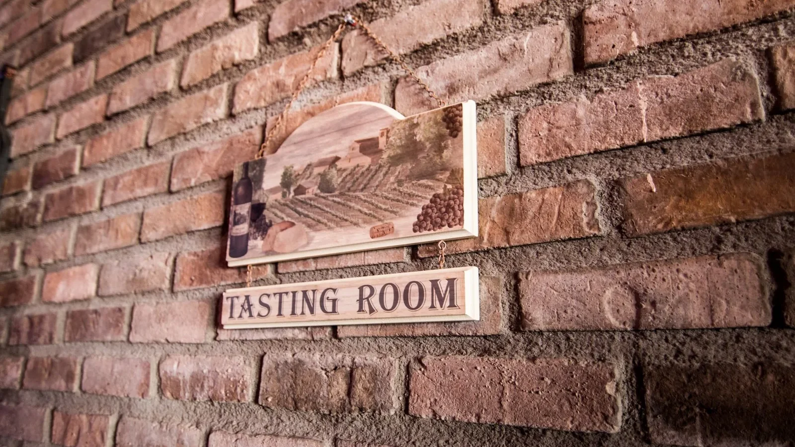 A quaint tasting room sign on a rustic brick wall creates a vintage ambiance