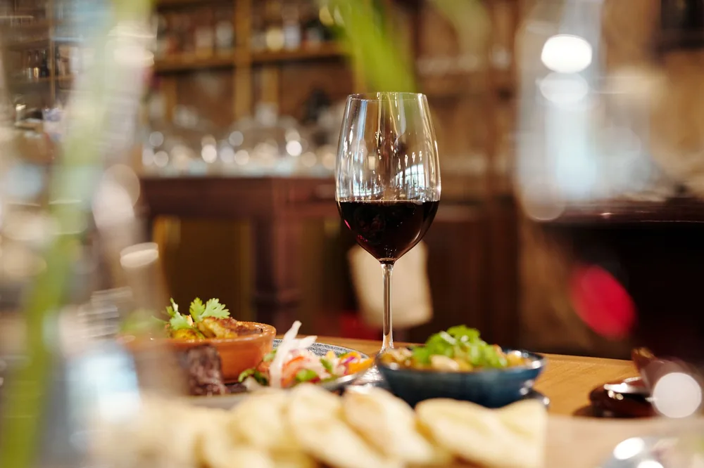 A red wine glass amidst a variety of appetizing dishes on a restaurant table