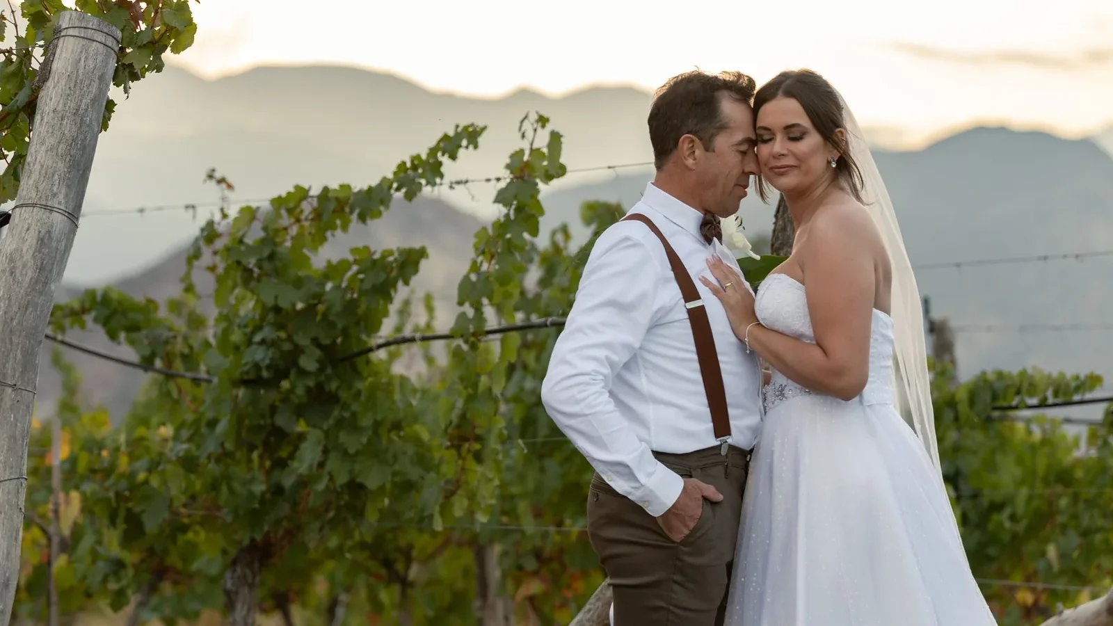 A romantic moment between a bride and groom in a vineyard landscape during sunset