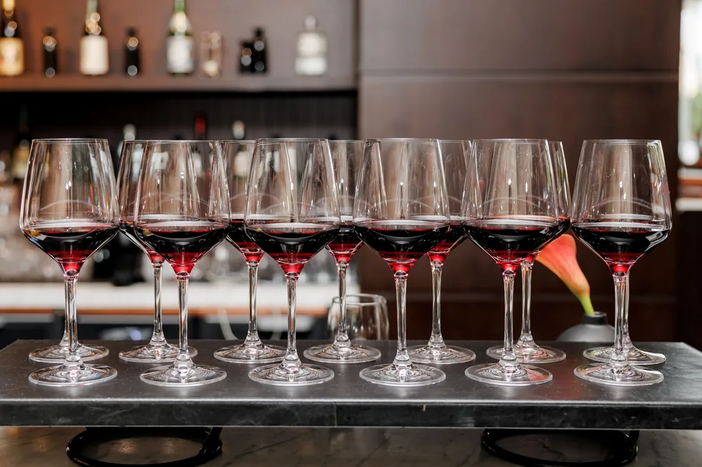 A row of red wine glasses elegantly arranged on a bar counter, creating a sophisticated ambience
