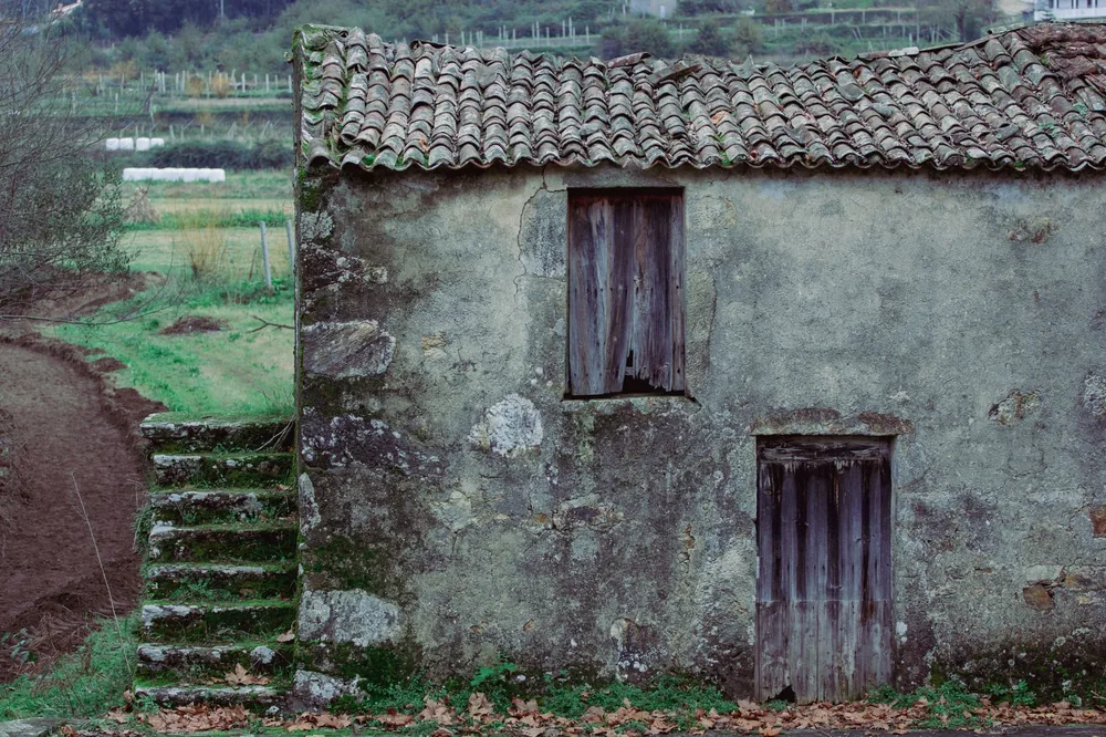A rustic, abandoned house with a weathered facade in a rural landscape