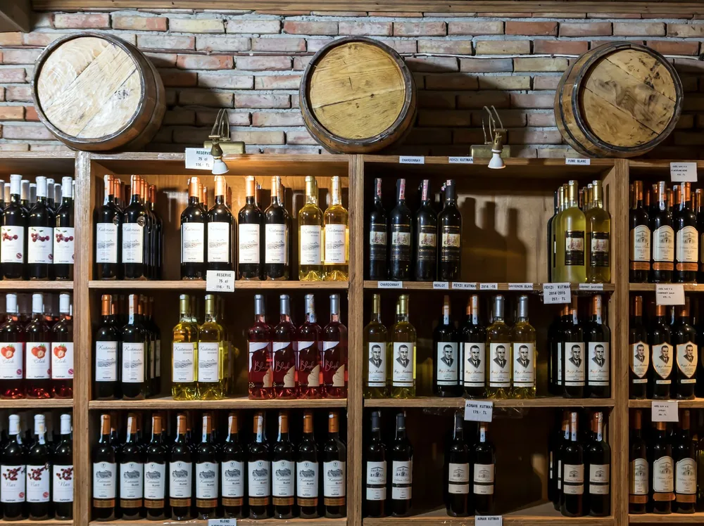 A rustic wine cellar showcasing a variety of wine bottles against a brick wall and wooden barrels