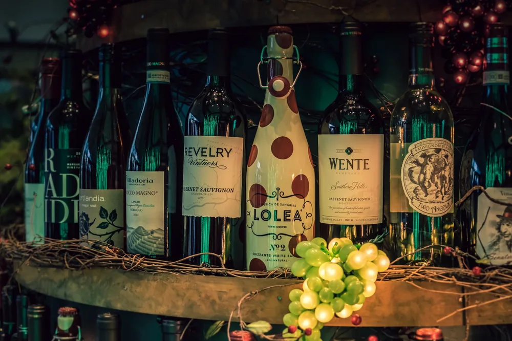 A showcase of assorted wine bottles displayed on a rustic shelf with decorative grapevine