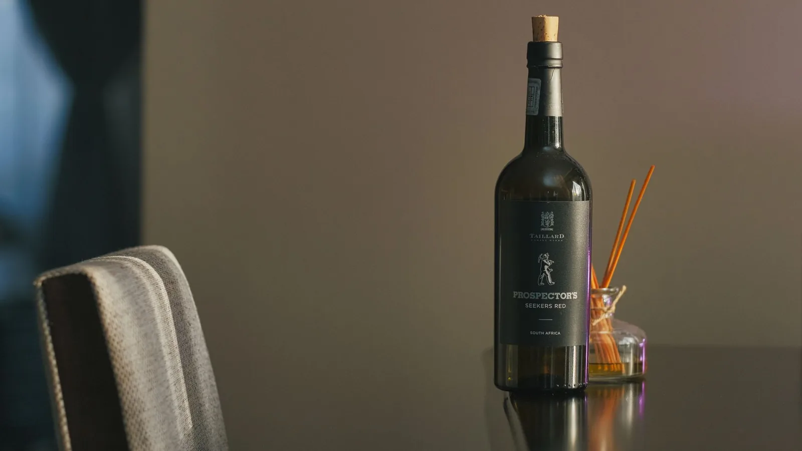 A sleek bottle of red wine with a calm background and decorative sticks beside it