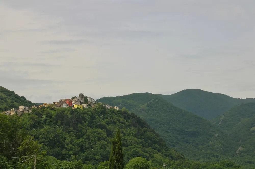 A small village located on a high hill that is part of a very green mountain range