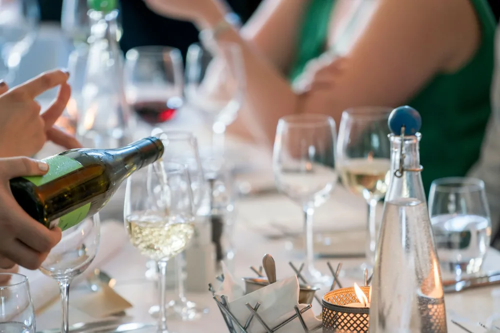 A sophisticated dinner setting with a focus on wine pouring creates a luxurious dining ambiance