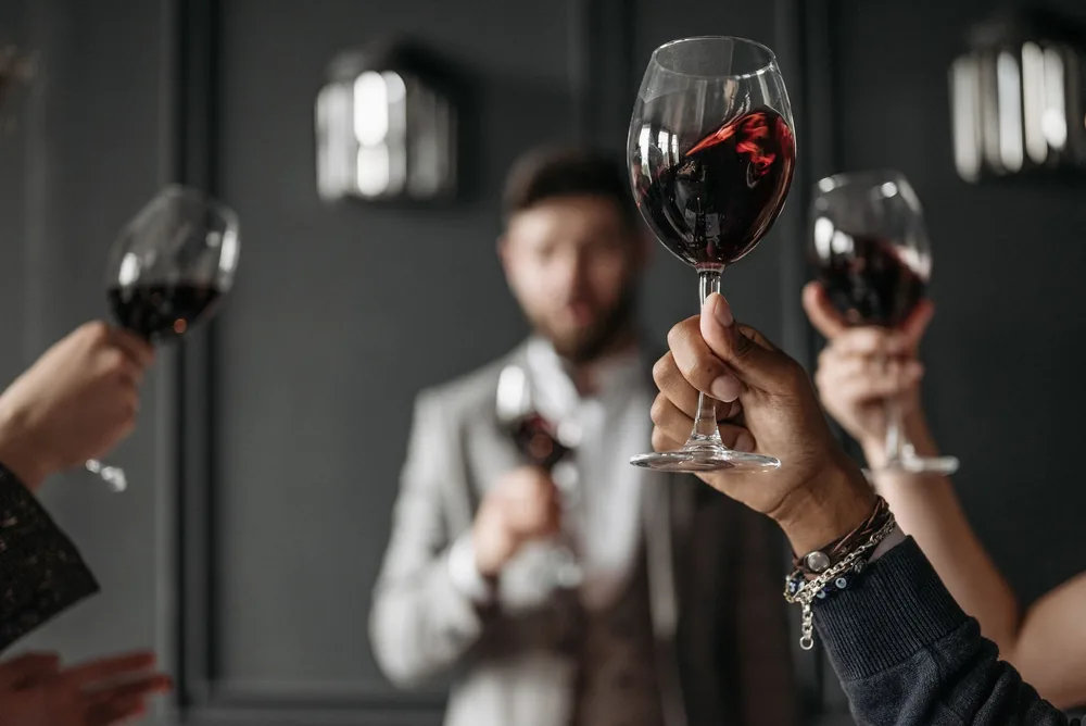 A sophisticated gathering with friends toasting with red wine in elegant glasses