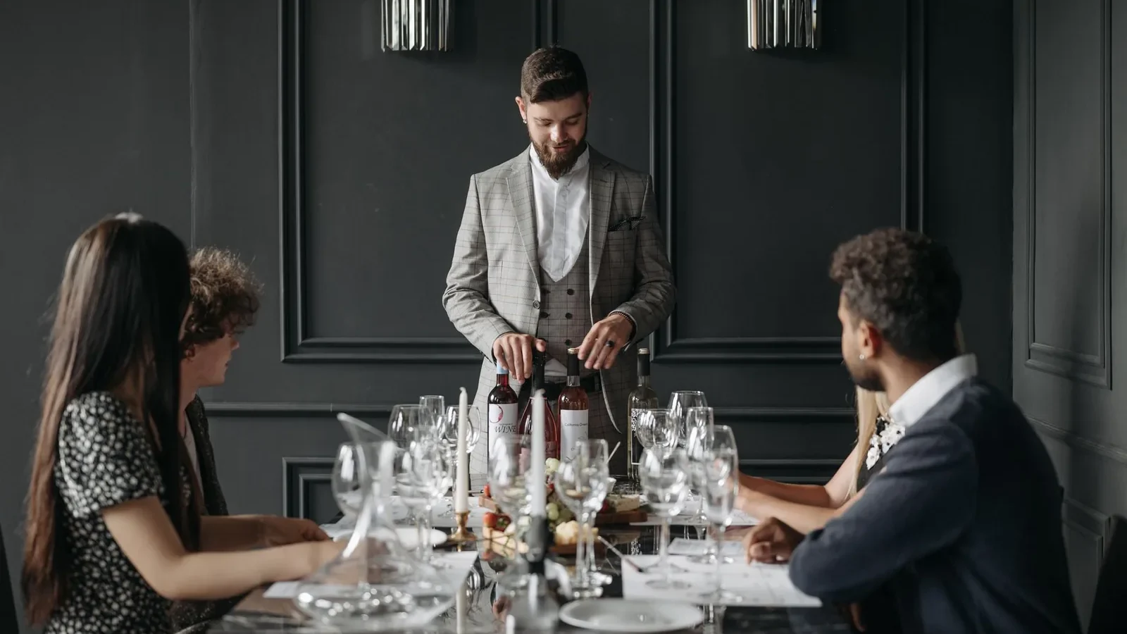 A sophisticated indoor dining setup with a sommelier presenting wine to seated guests