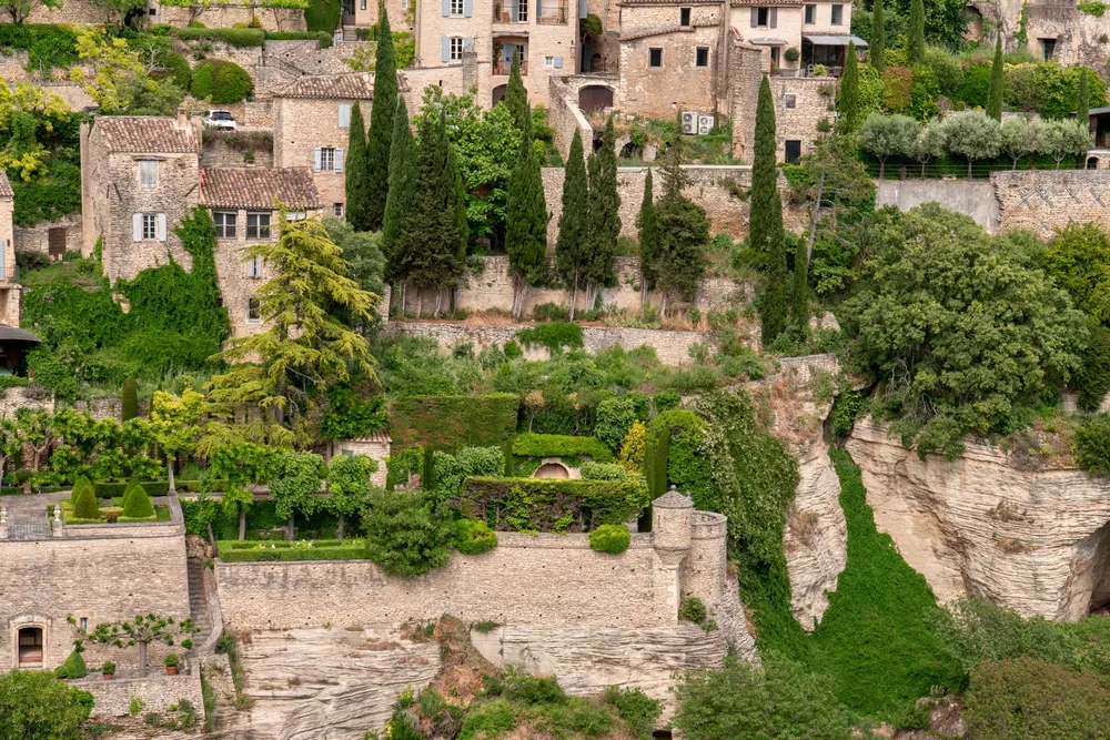 A stone village with lush greenery nestled in a hillside, exuding old-world charm