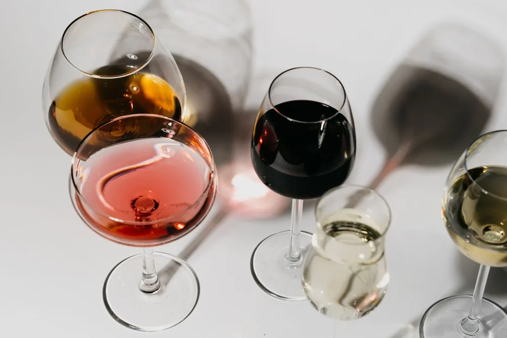 A variety of wine glasses on a clean white surface, showcasing different types and colors of wine