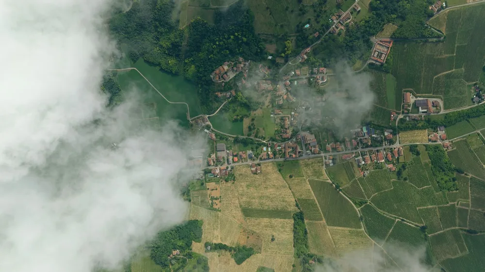 A village and fields amidst white clouds