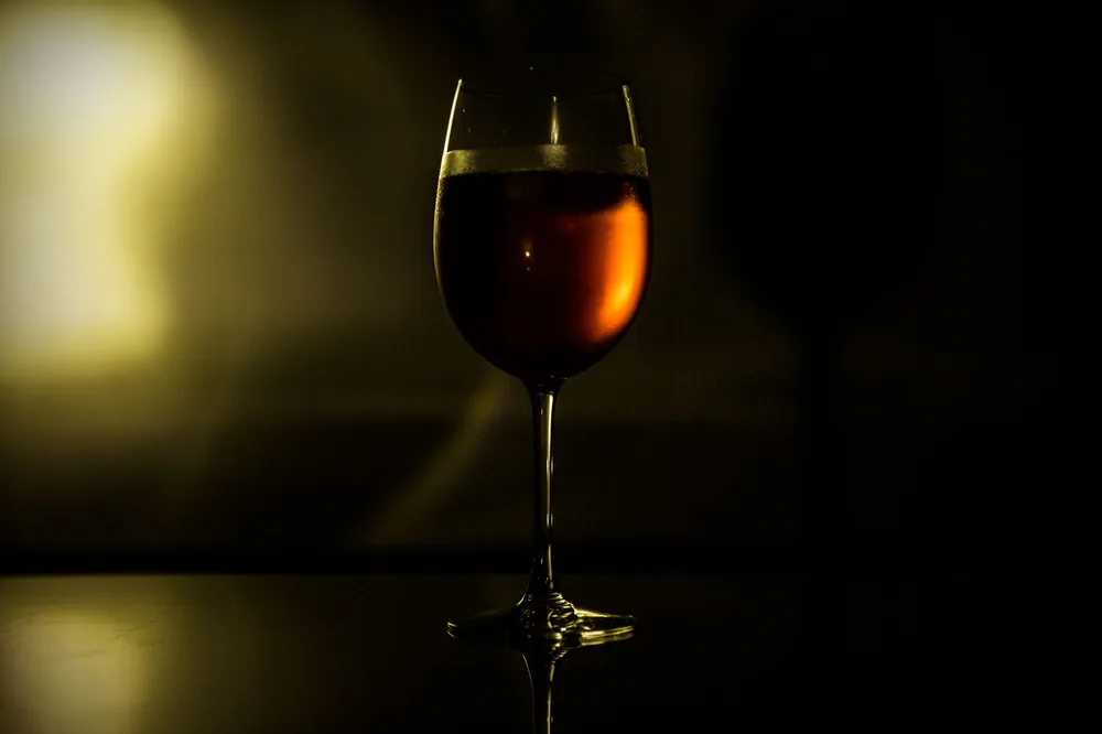A warm and artistic shot of a wine glass illuminated in dim light, creating a sophisticated ambiance
