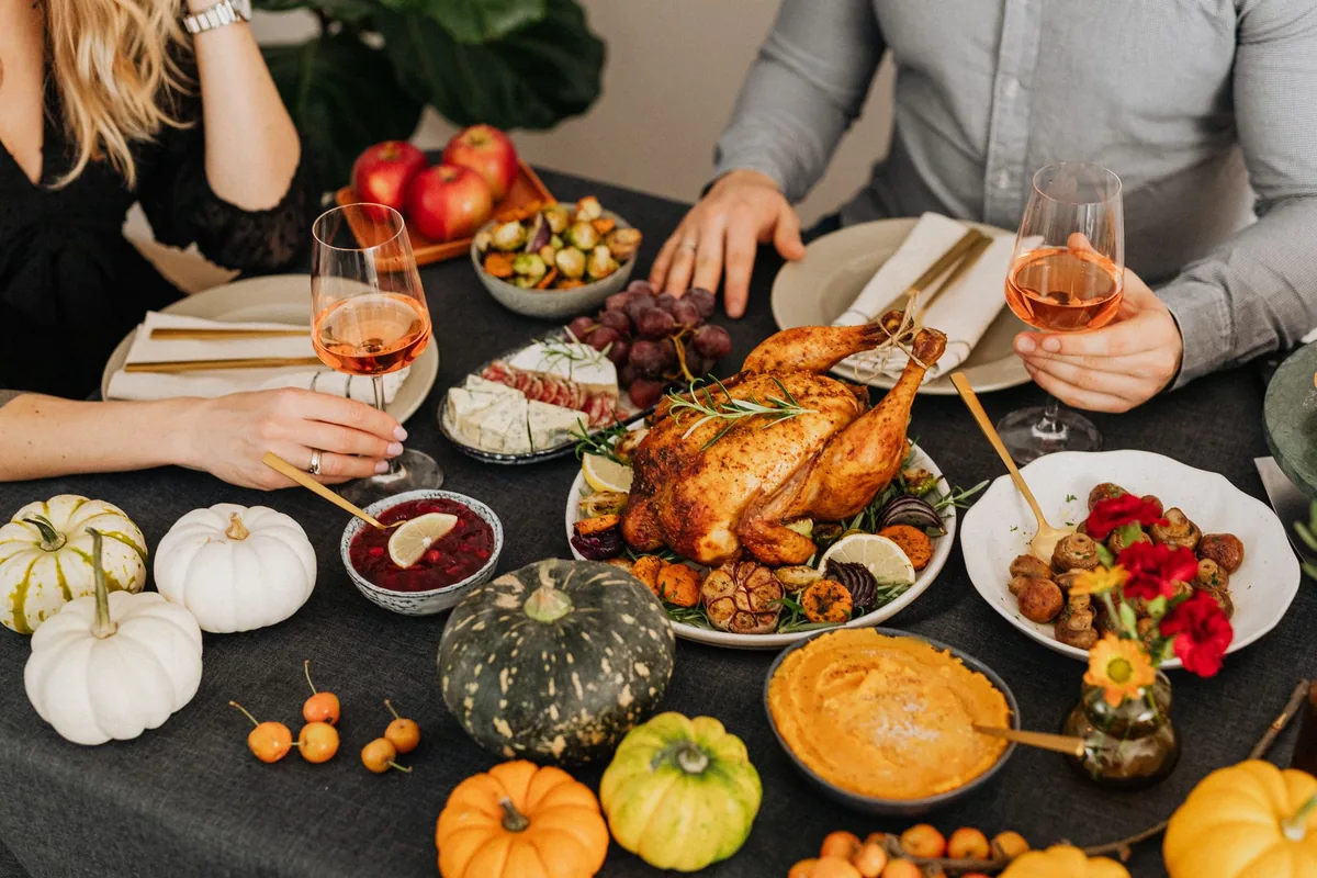 A warm and inviting Thanksgiving dinner setup featuring turkey, wine, and autumn vegetables