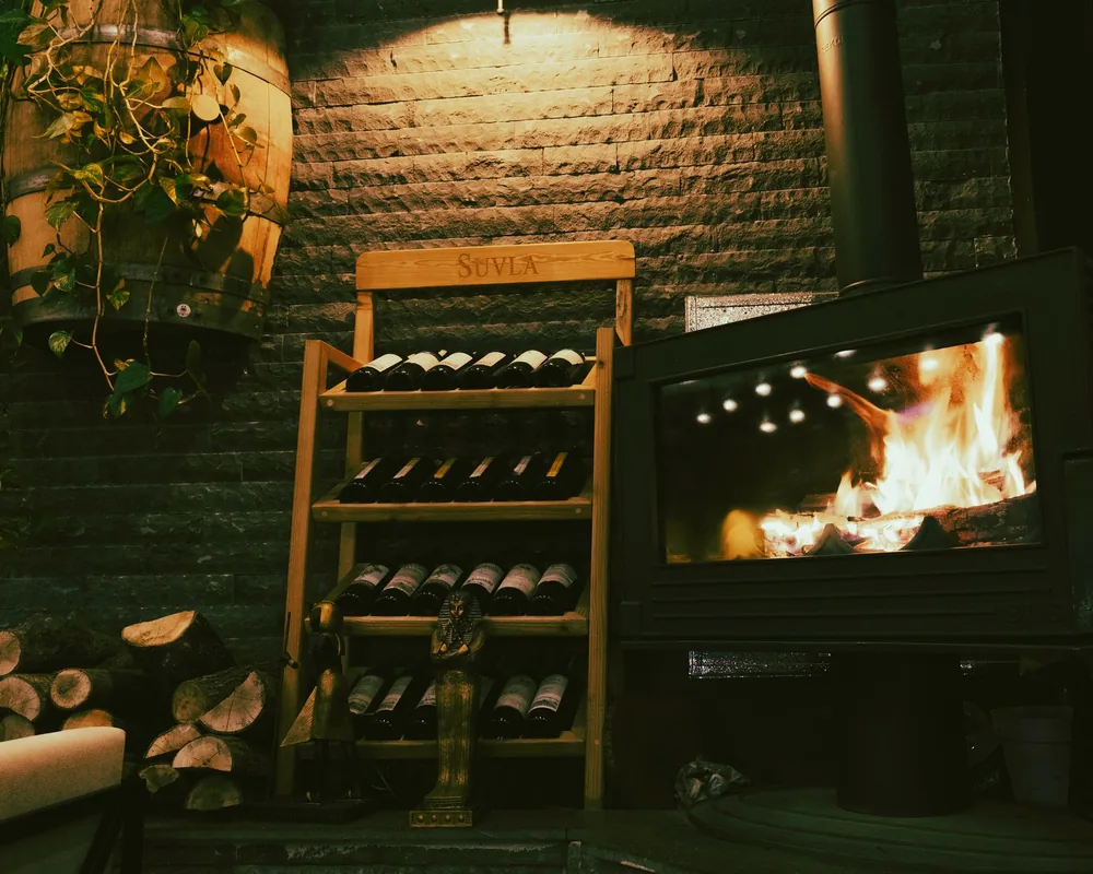 A warm and inviting wine cellar interior featuring a wine rack, fireplace, and decorative elements