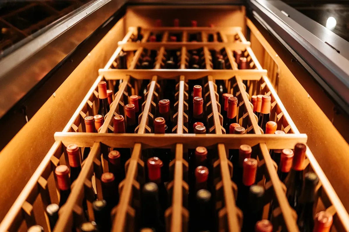 A warm-toned close-up of bottled wine stored in a wooden rack, perfect for a winery or wine cellar concept