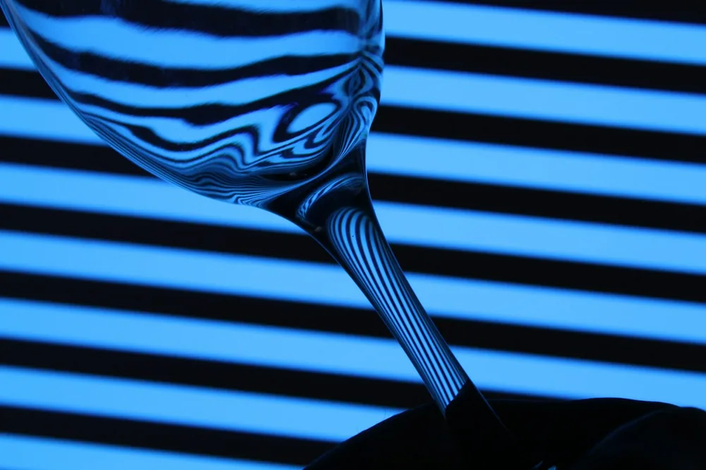 A wine glass reflects blue, striped light
