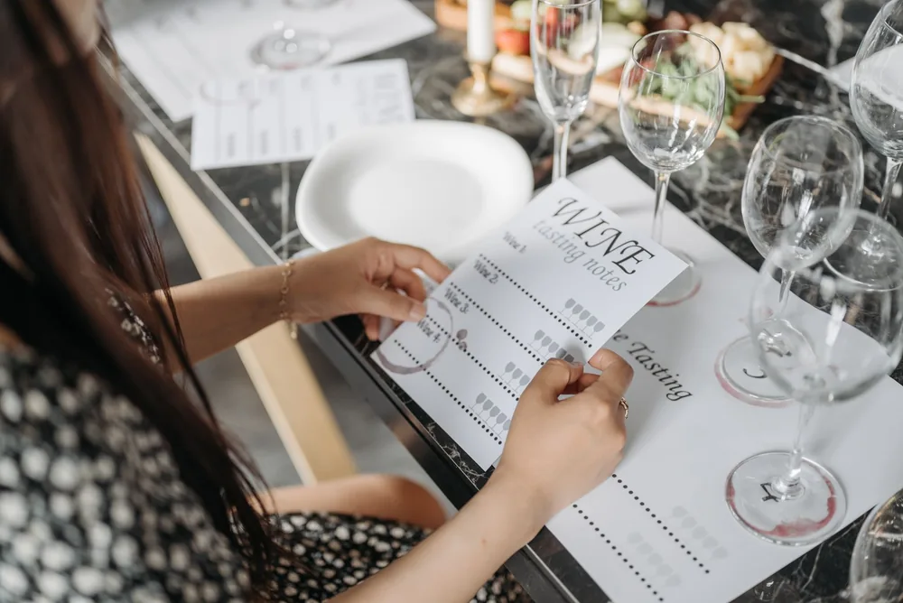 A woman exploring wine tasting notes at an elegantly arranged table in preparation for a wine tasting event